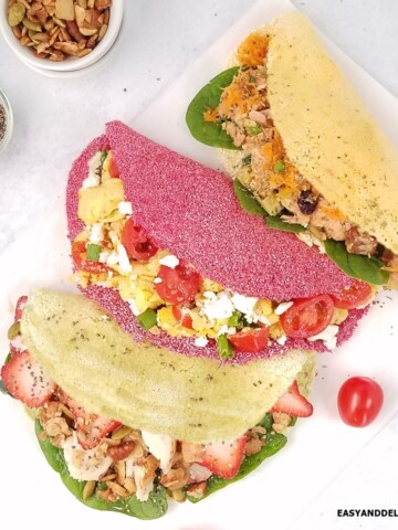 Three colorful Brazilian tapioca crepes with fillings.
