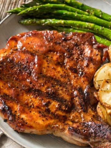 Glazed pork chop served with roasted potatoes and asparagus.