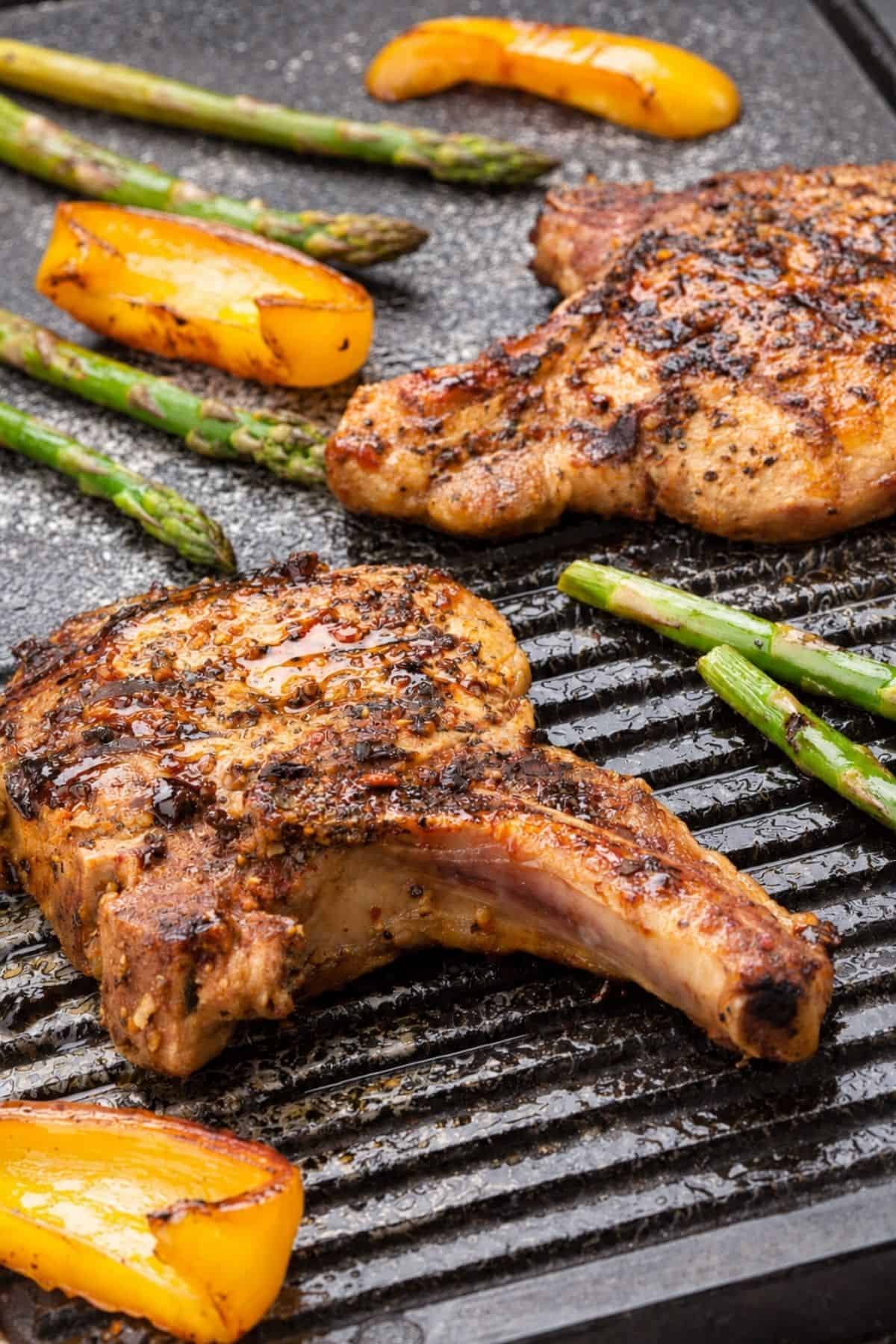 Bone-in Pork Chops on Blackstone with asparagus and peppers.