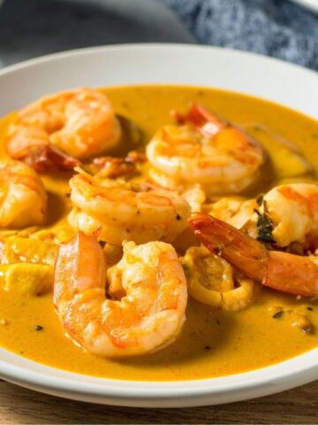 Delicious creamy shrimp curry with sriracha sauce in a white bowl.