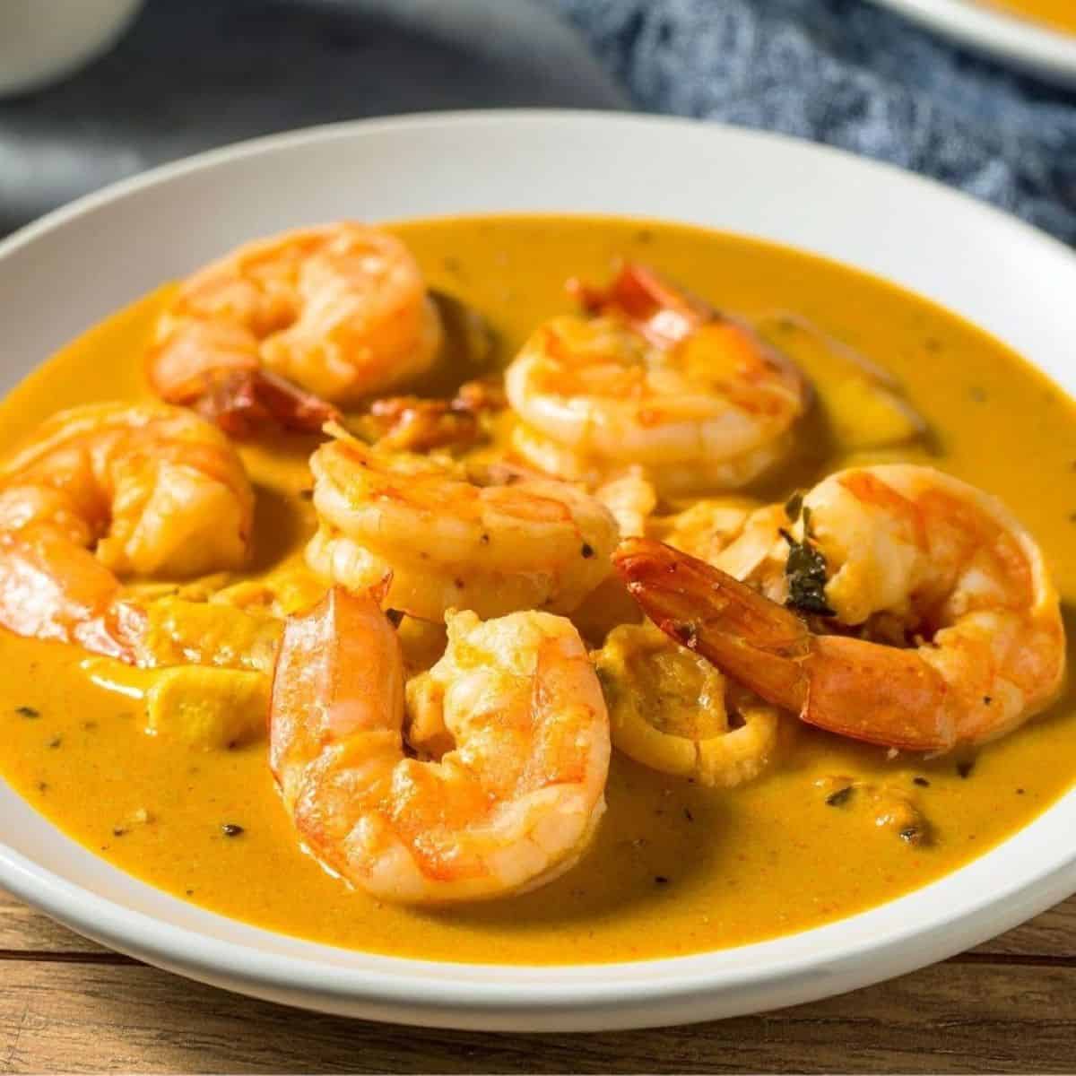 Delicious creamy shrimp curry with sriracha sauce in a white bowl.