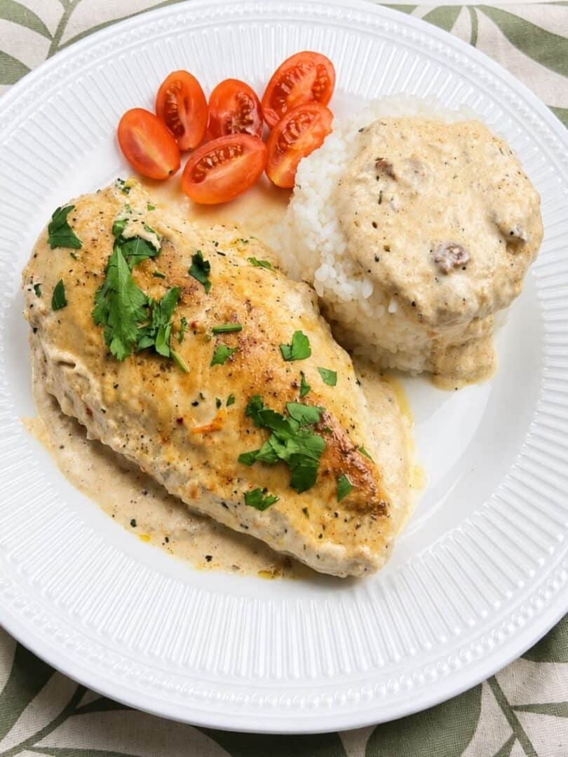 Easy creamy chicken dinner served with white rice, cherry tomatoes, and parsley.