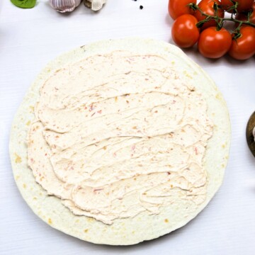 Spreading the cream cheese over the tortilla.