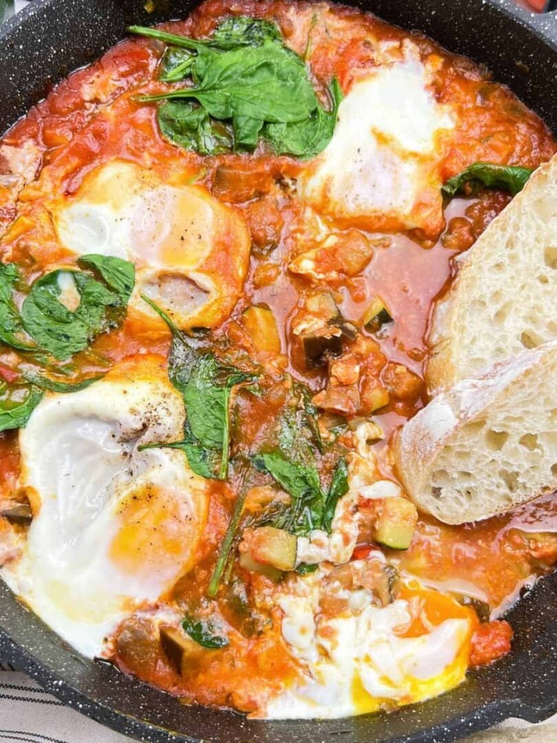 Mediterranean eggplant shakshuka with eggs in tomato sauce in skillet.