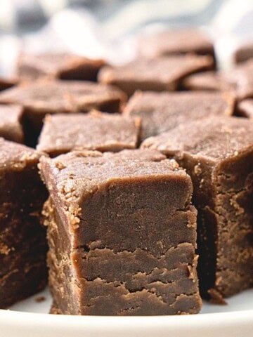 Rich ganache-style chocolate peanut butter fudge cubes on a white plate.