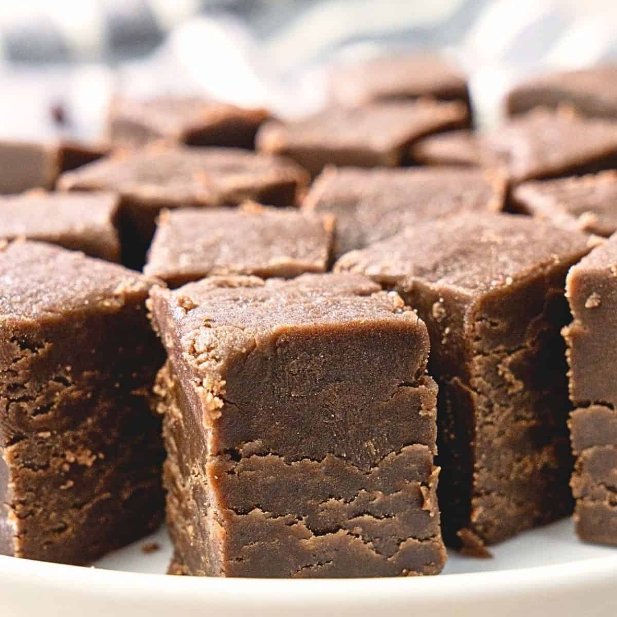 Rich ganache-style chocolate peanut butter fudge cubes on a white plate.