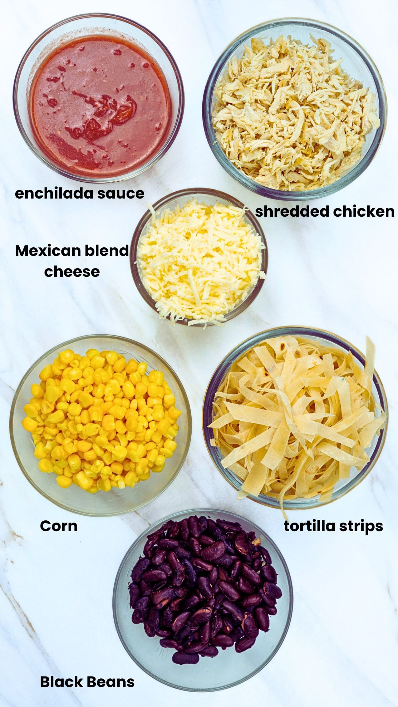 Ingredients for chicken skillet enchiladas including chicken, enchilada sauce, black beans, corn, tortilla strips, and cheese.