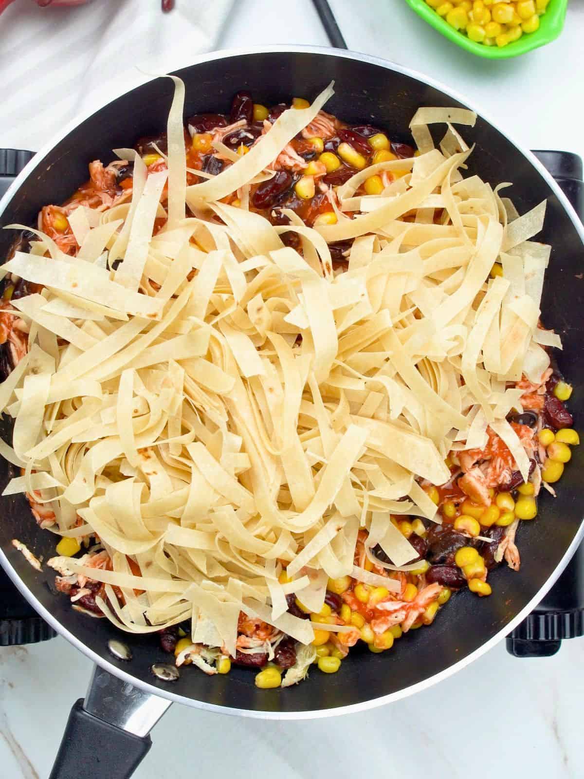 Tortilla strips mixed into chicken skillet enchiladas.