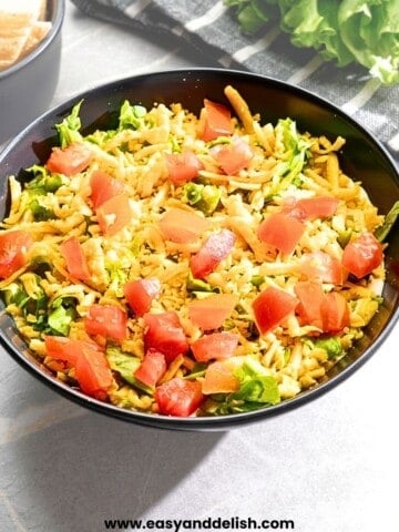 taco dip with cream cheese lettuce and cheddar cheese in dish.