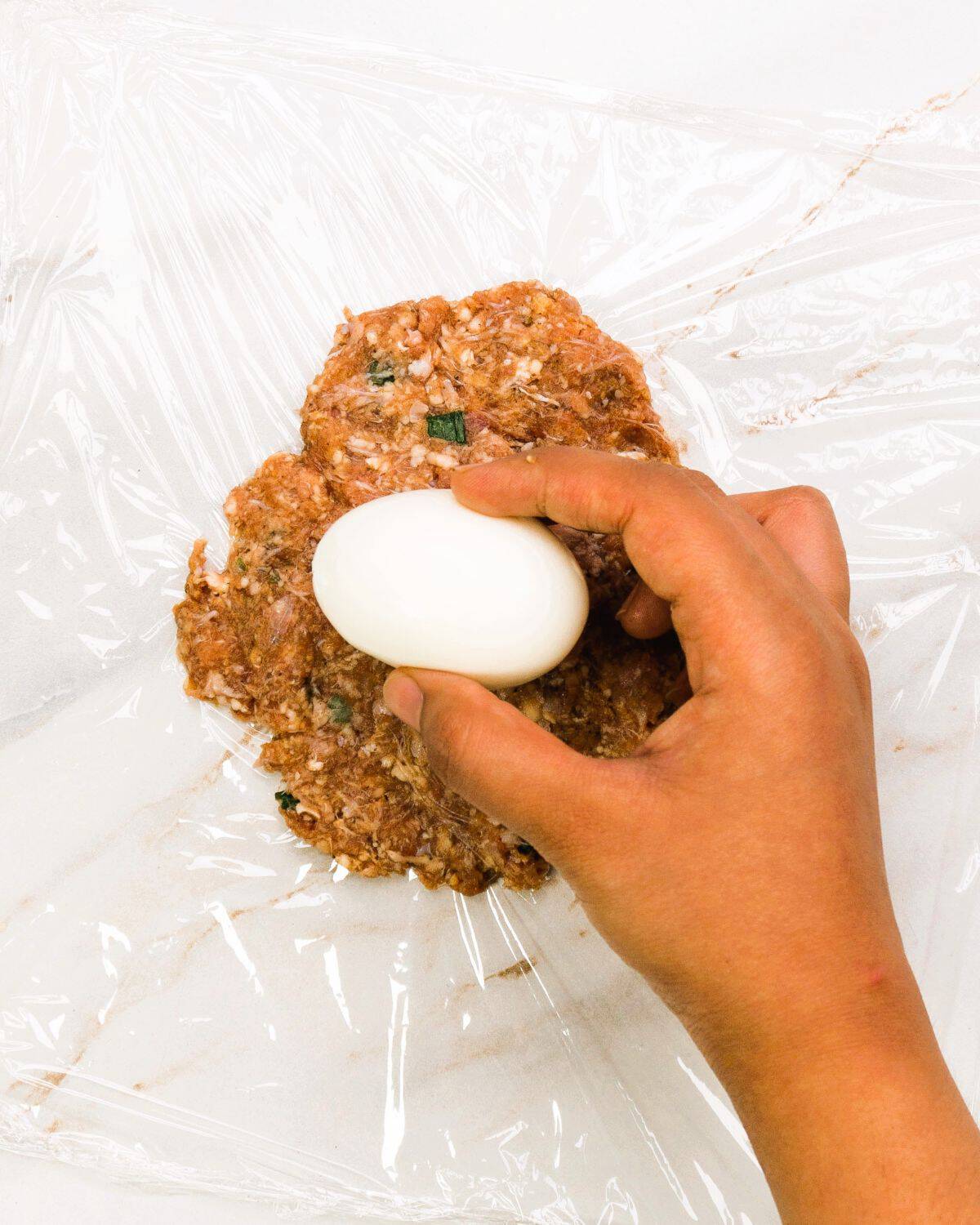 Wrap the eggs for the Ground Beef Scotch Eggs Step 3.