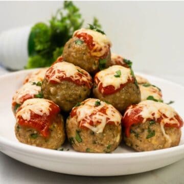 Baked Chicken Parmesan Meatballs served with marinara sauce and fresh parsley.
