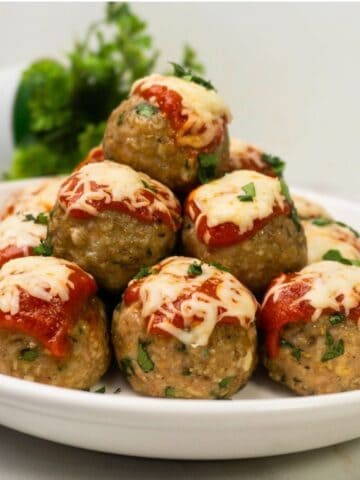 Baked Chicken Parmesan Meatballs served with marinara sauce and fresh parsley.