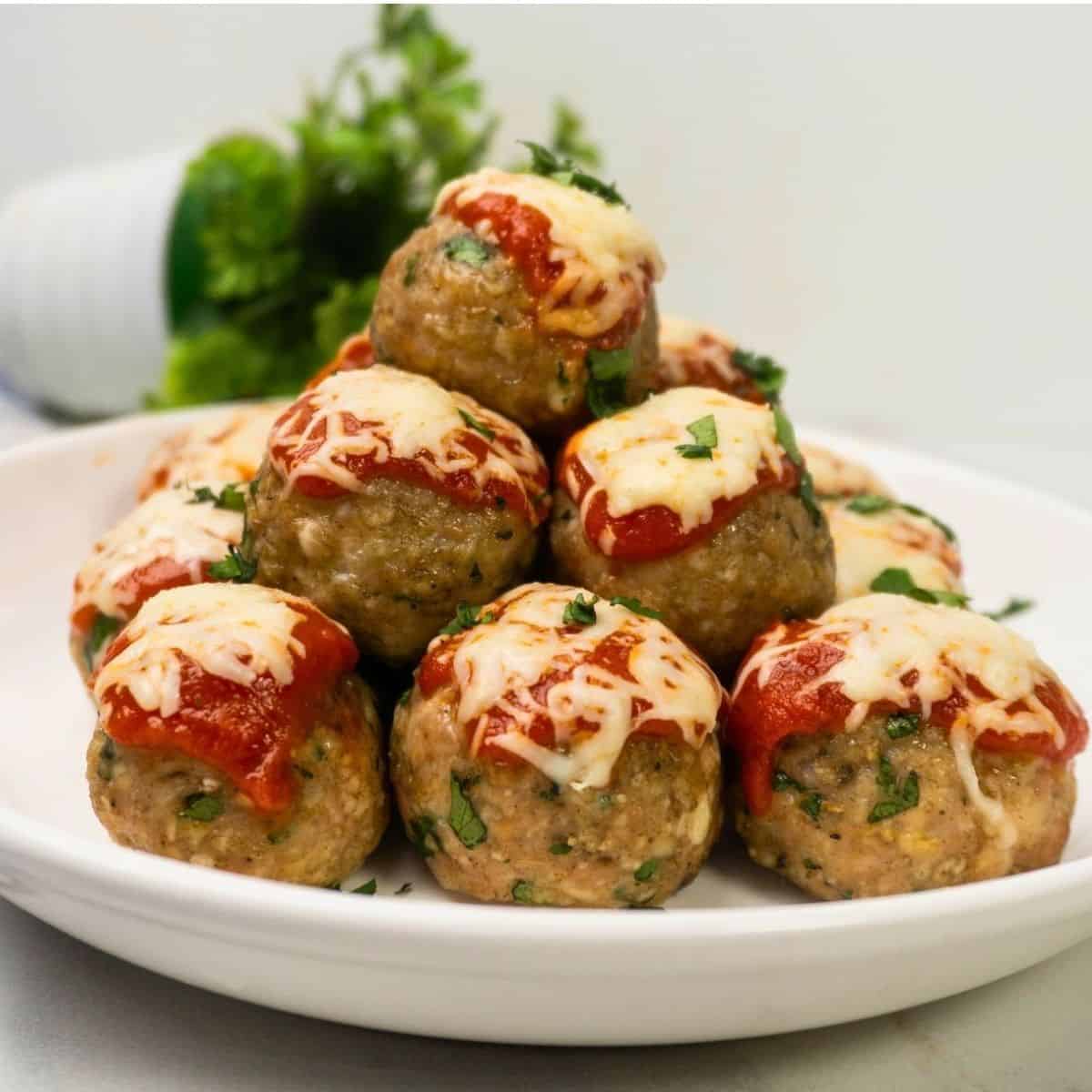 Baked Chicken Parmesan Meatballs served with marinara sauce and fresh parsley
