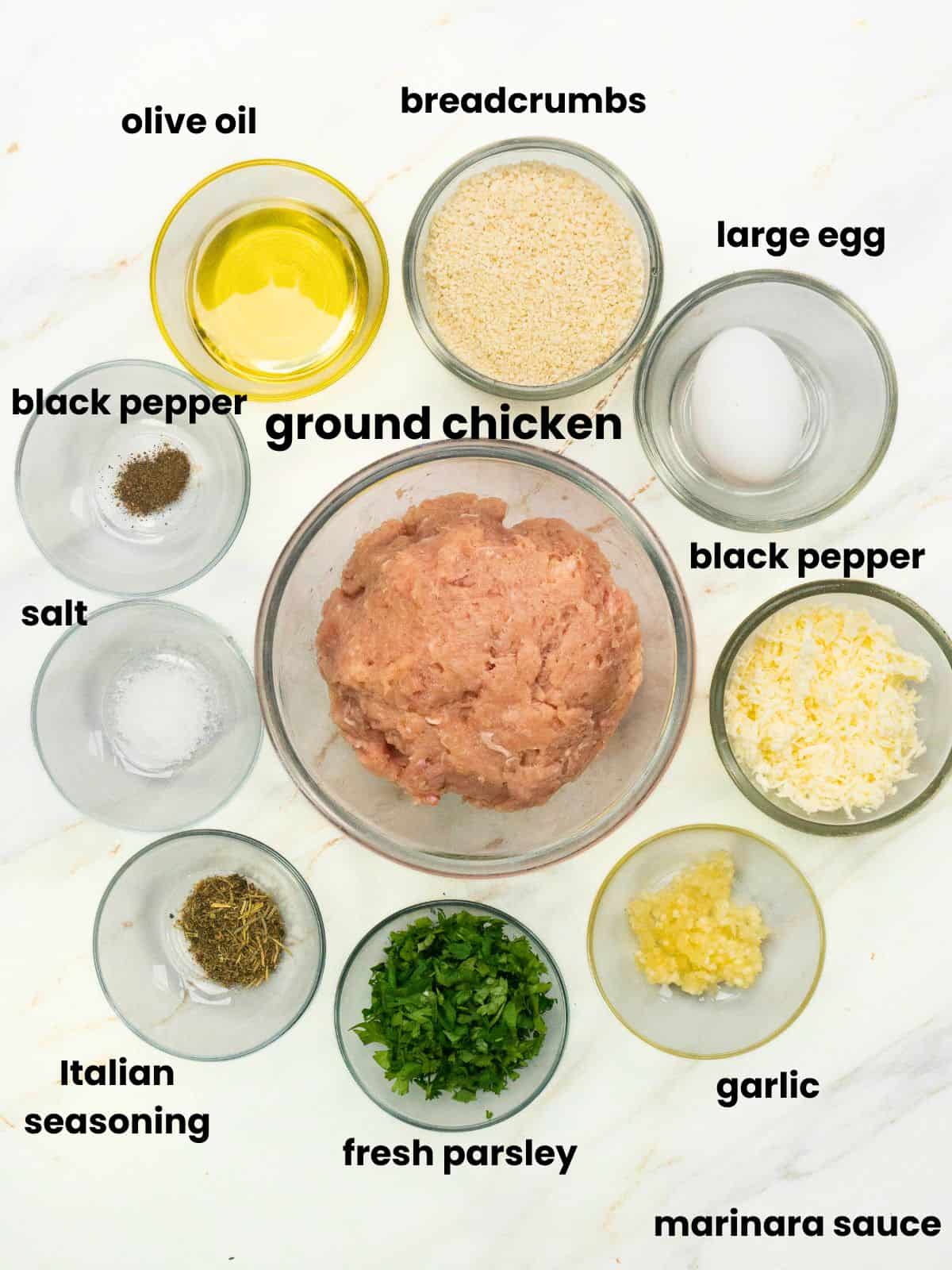 Ingredients for baked chicken Parmesan meatballs including ground chicken, Parmesan cheese, breadcrumbs, garlic, parsley, and seasonings.