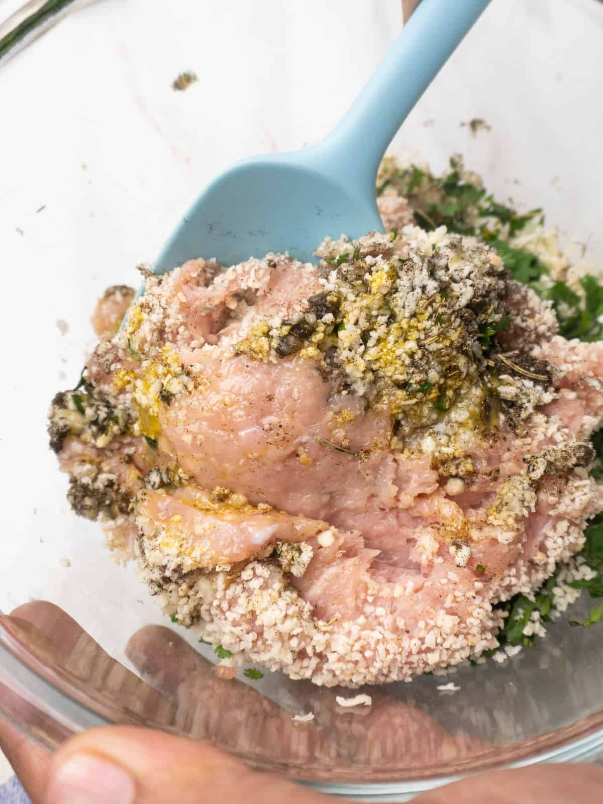 Adding ingredients to a bowl for baked chicken Parmesan meatballs.