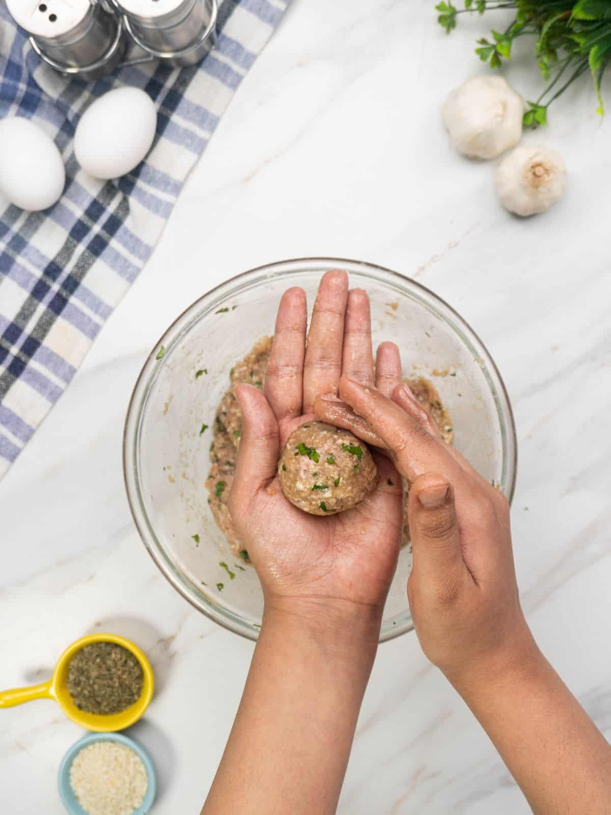 Shaping chicken Parmesan meatballs before baking.