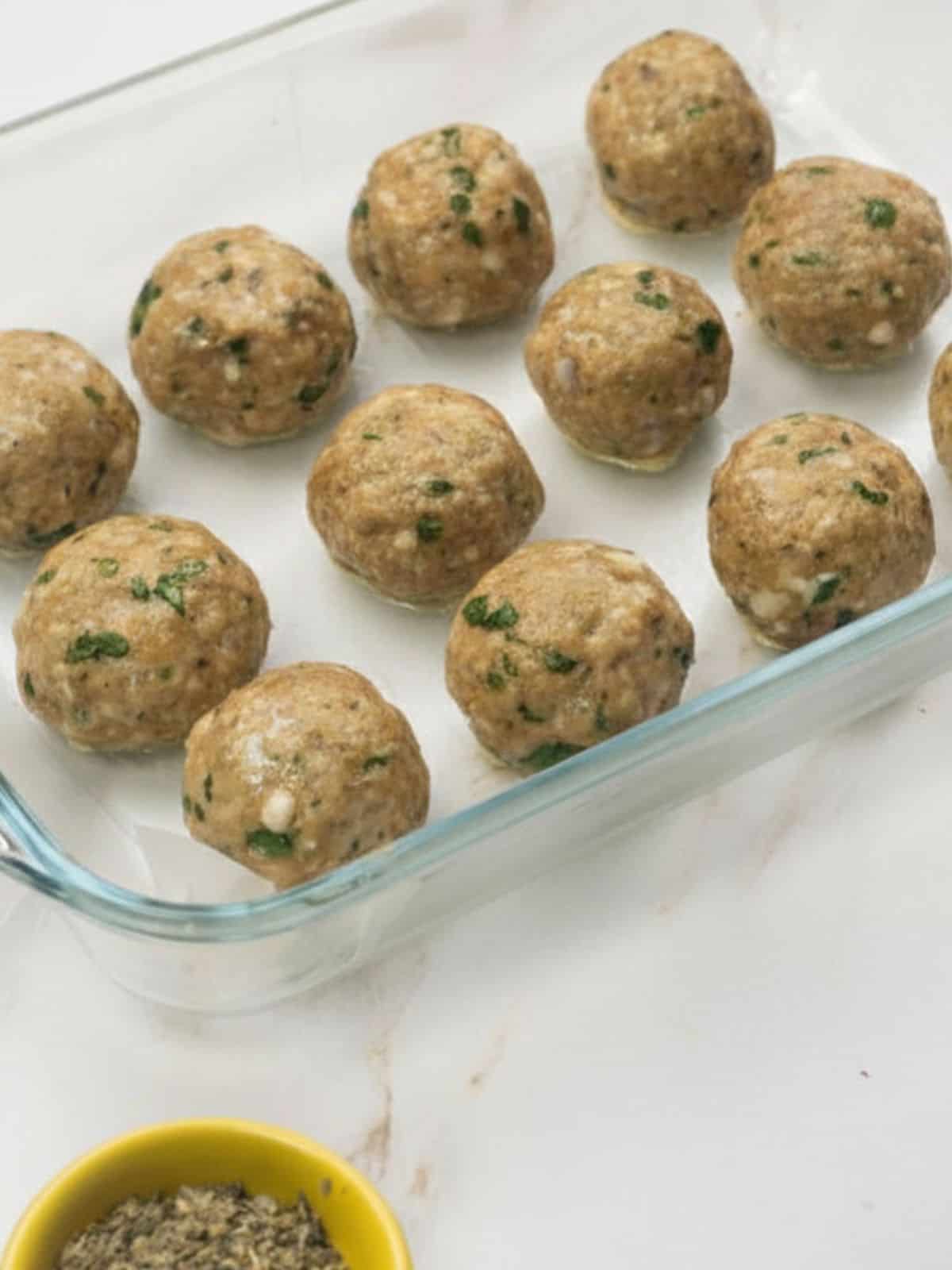 Golden baked chicken Parmesan meatballs on a baking sheet.