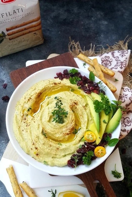 Creamy avocado hummus garnished with dried cranberries and fresh parsley, served as an easy Christmas appetizer.