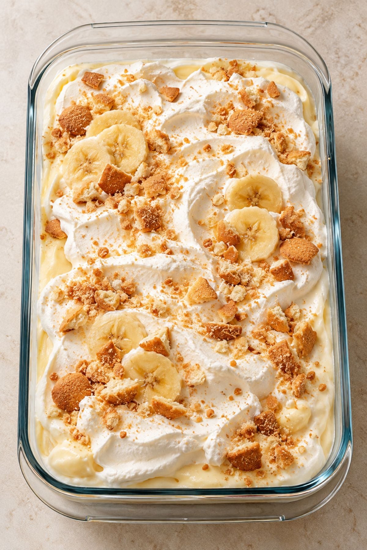 Banana Pudding in a rectangular glass baking dish, topped with whipped cream, banana slices, and crushed vanilla wafers.