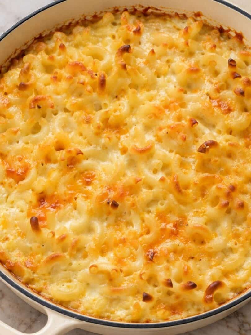 Baked macaroni and cheese with melted cheddar and a golden-brown top in a skillet.