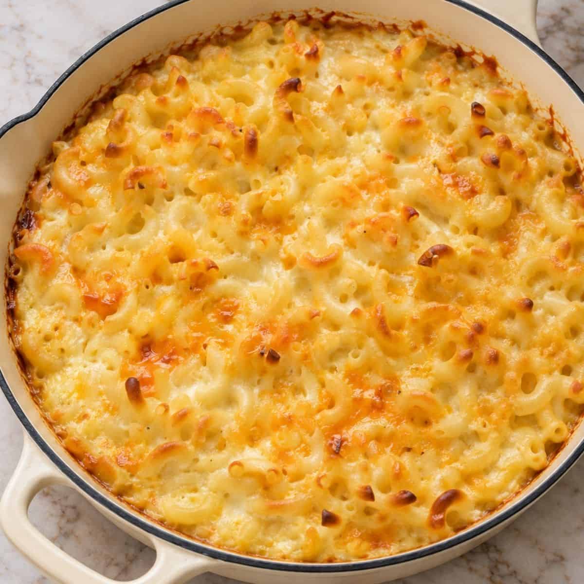 Baked macaroni and cheese with melted cheddar and a golden-brown top in a skillet.
