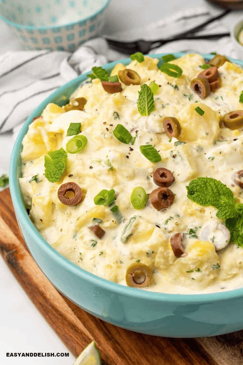 Creamy Brazilian potato salad with mayonnaise, chopped olives, and fresh herbs served in a bowl for Christmas dinner.