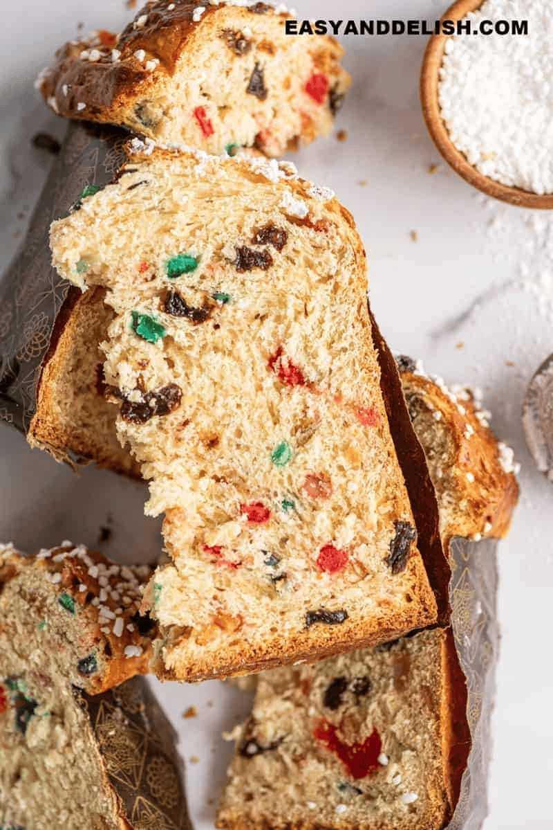 Homemade Christmas panettone sliced to reveal fluffy sweet bread filled with candied fruit and raisins, alongside a chocolate chip variation.