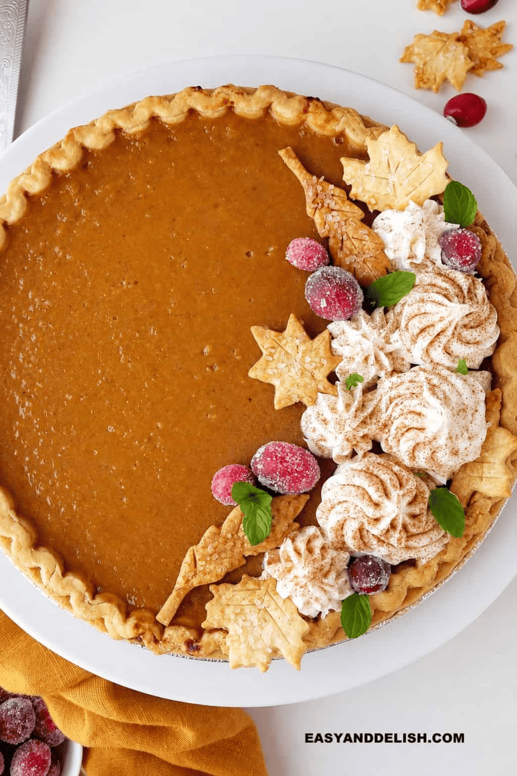 Southern sweet potato pie with a golden flaky crust and smooth spiced sweet potato filling, topped with whipped cream and cranberries.