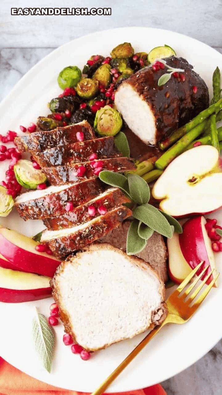 Sliced crock pot pork loin roast with honey-balsamic sauce, arranged on a serving platter for Christmas dinner.