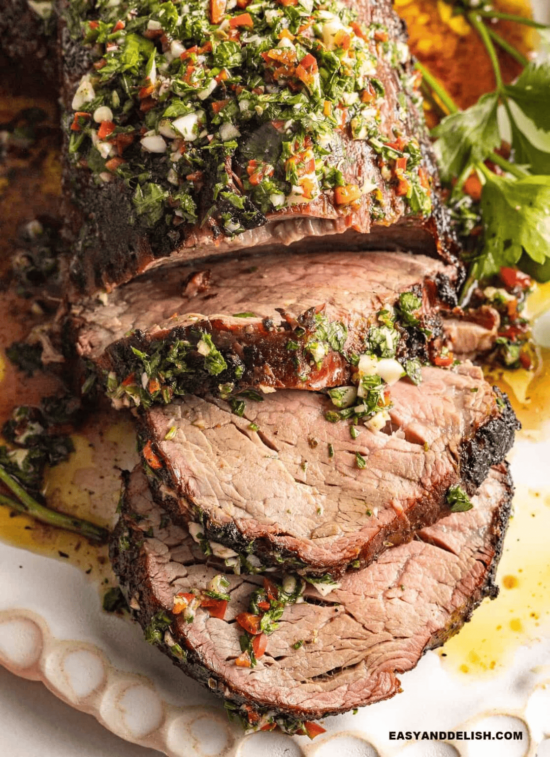 Sliced smoked beef tenderloin with a browned crust and juicy pink center, served on a platter.