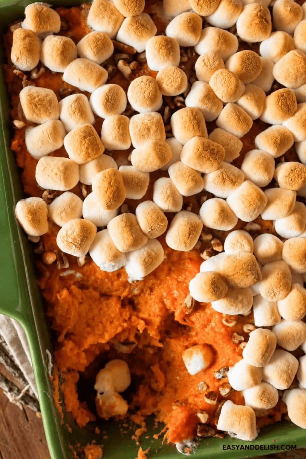 Baked sweet potato casserole topped with golden toasted marshmallows and crunchy pecan streusel in a serving dish.